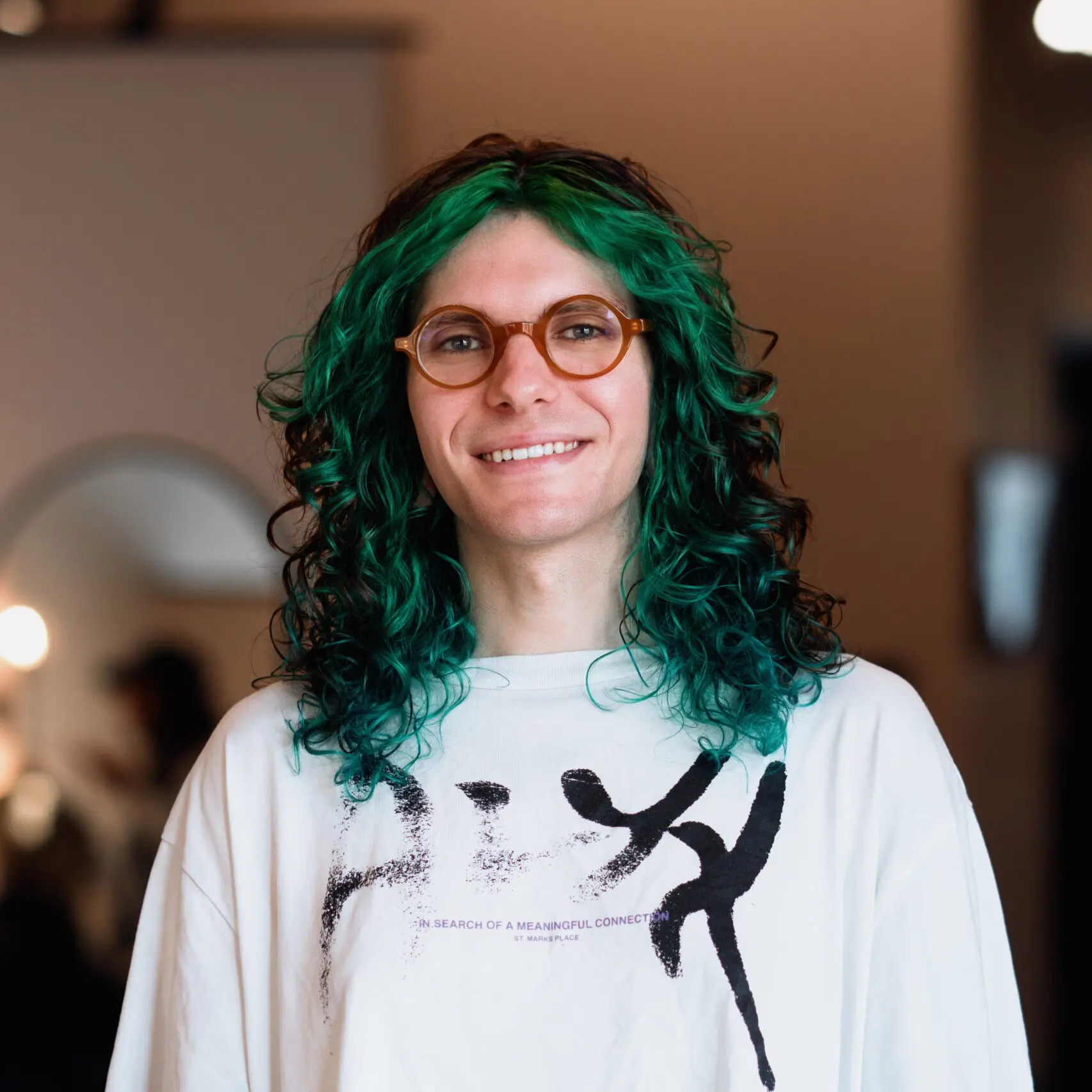 Smiling person with curly green hair